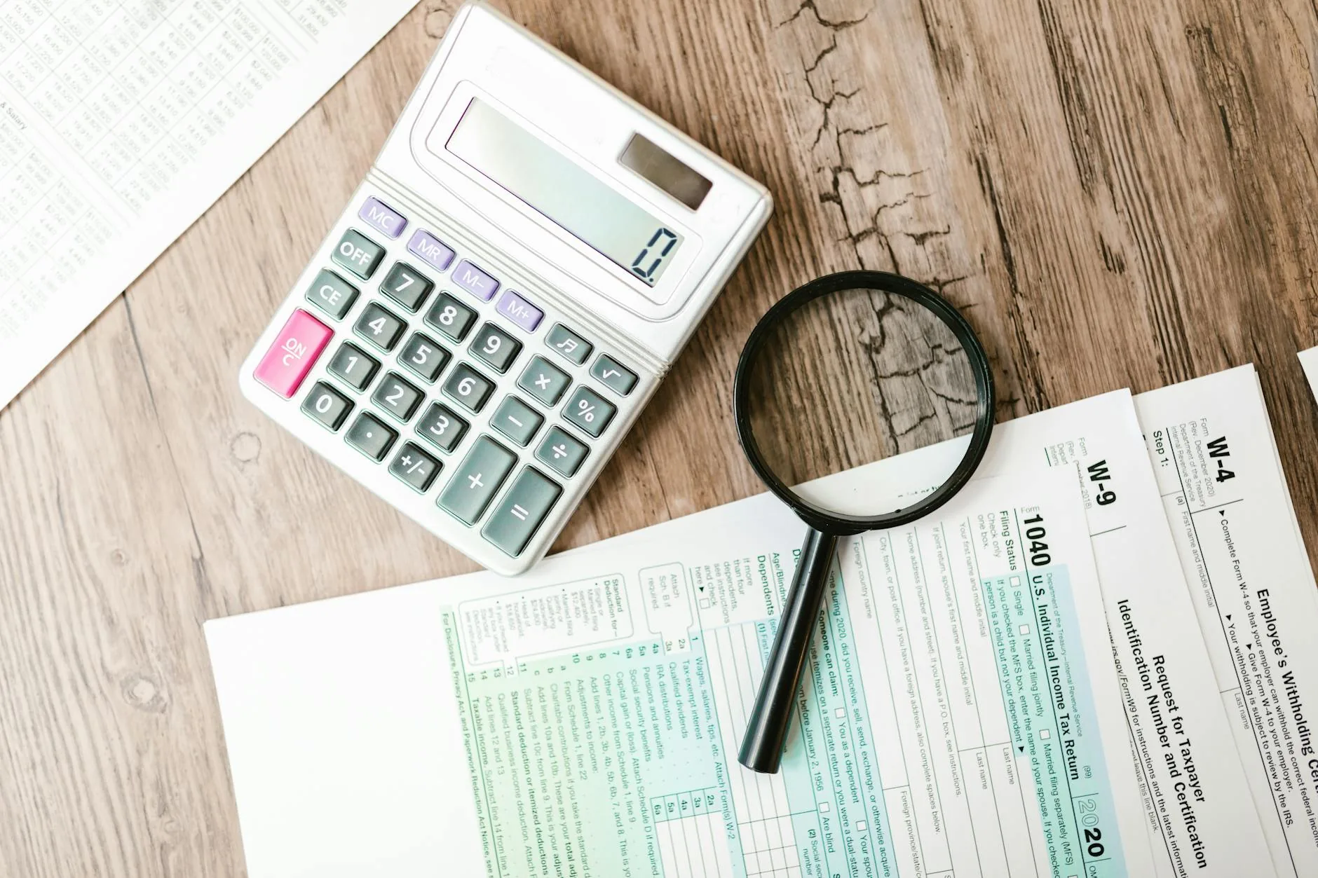 Tax forms, calculator, and pen laid out on a desk for filing