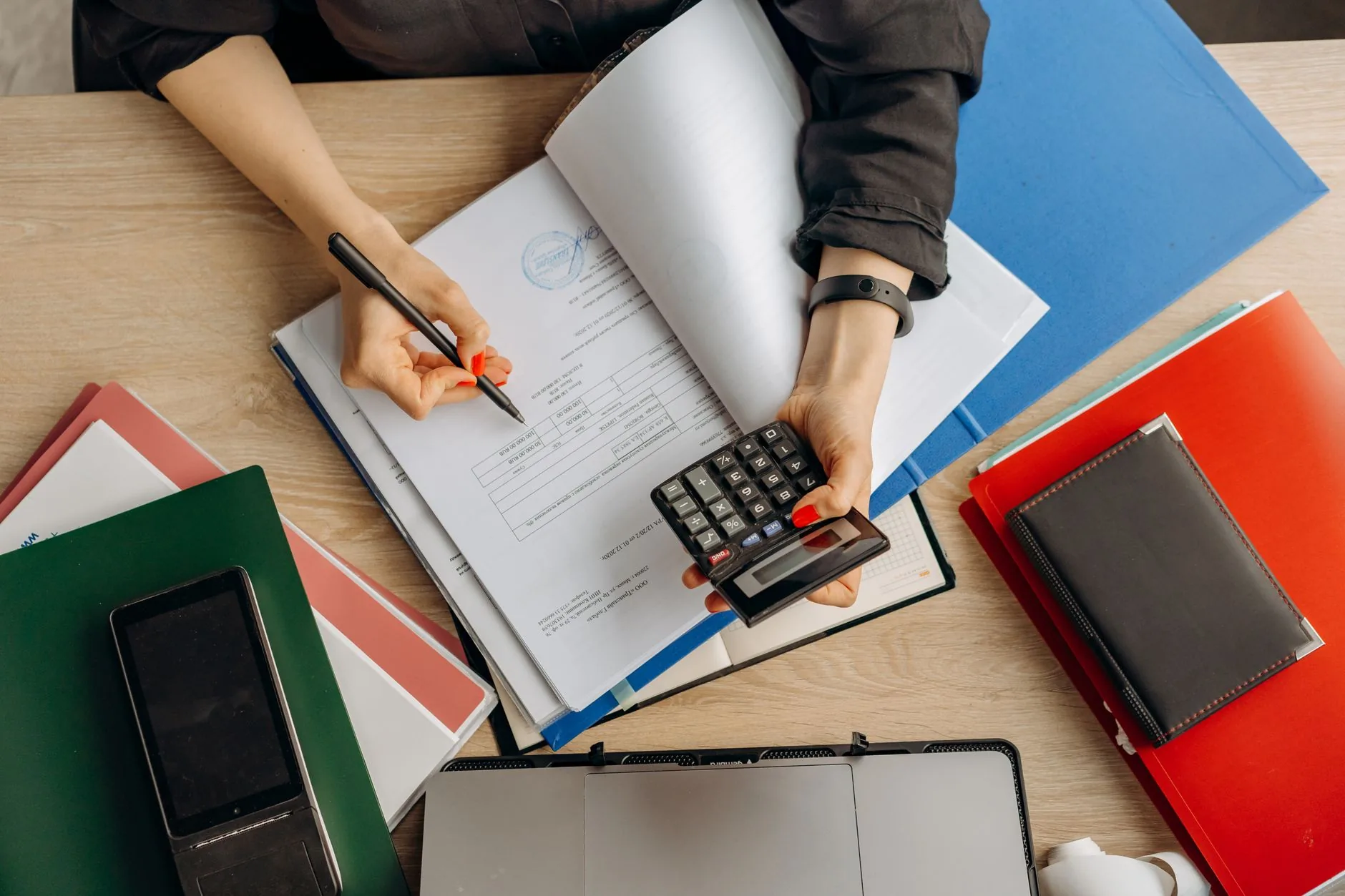 A small-business owner reviewing tax documents at a desk with a laptop and calculator