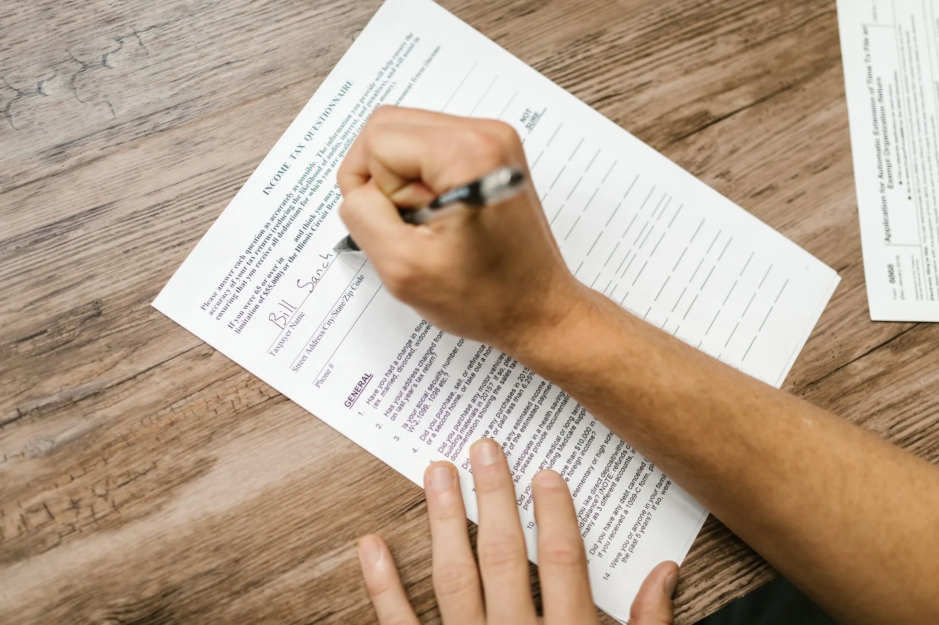 A person filling out a tax form at a desk with a calculator and documents