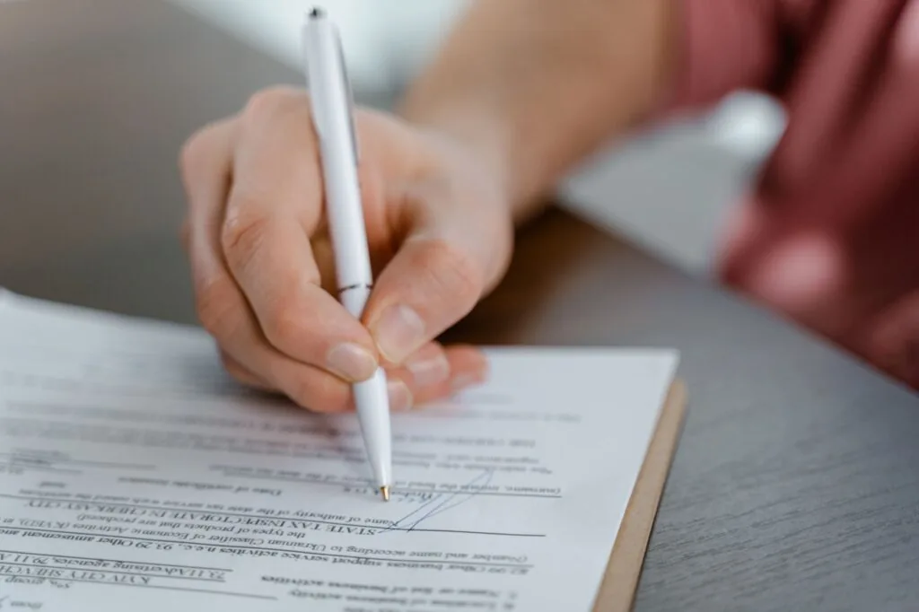 Close-up of a person signing an official document with a pen