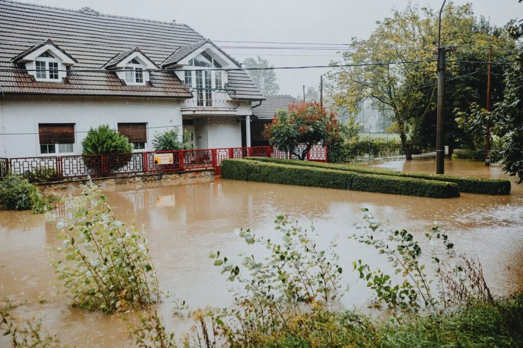 A flooded residential street with water surrounding homes after a storm