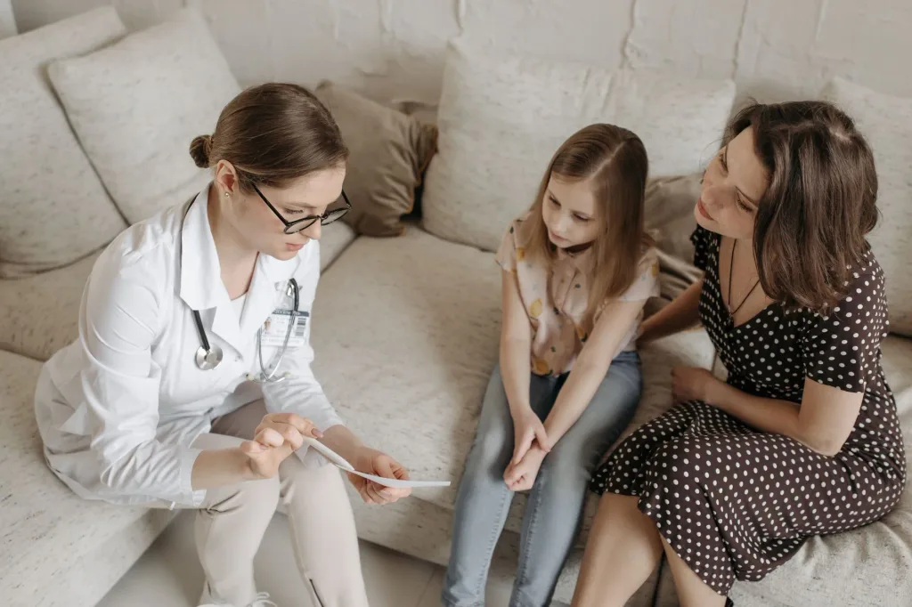 A health advisor sitting with a mother and daughter at home, reviewing coverage options