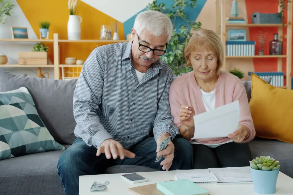 A retired couple at home reading their Medicare plan paperwork together before Annual Enrollment